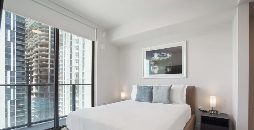 Comfortable queen bed with large windows and city views
