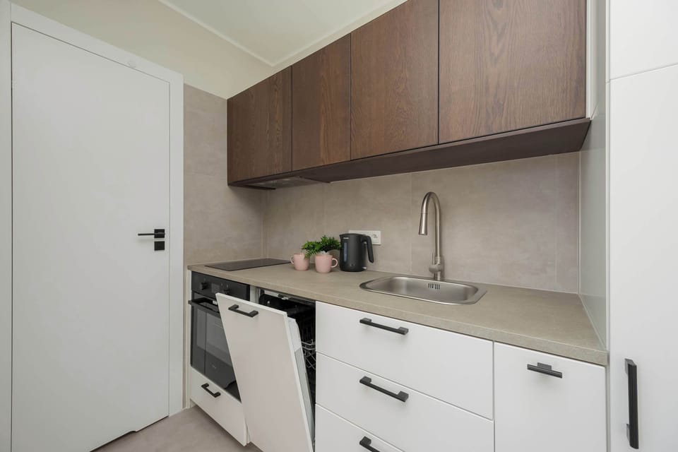 Looking into the kitchen from the side, the image reveals the integrated appliances and a sleek countertop. The bright white walls help maintain a clean and airy feeling in the narrow space.