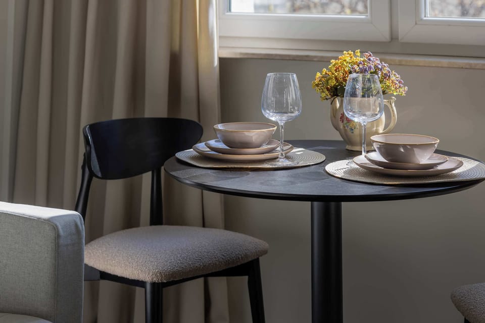 A white sofa and table with a potted plant are positioned in a sunlit corner. This close-up highlights the modern furniture and bright atmosphere of the living space.