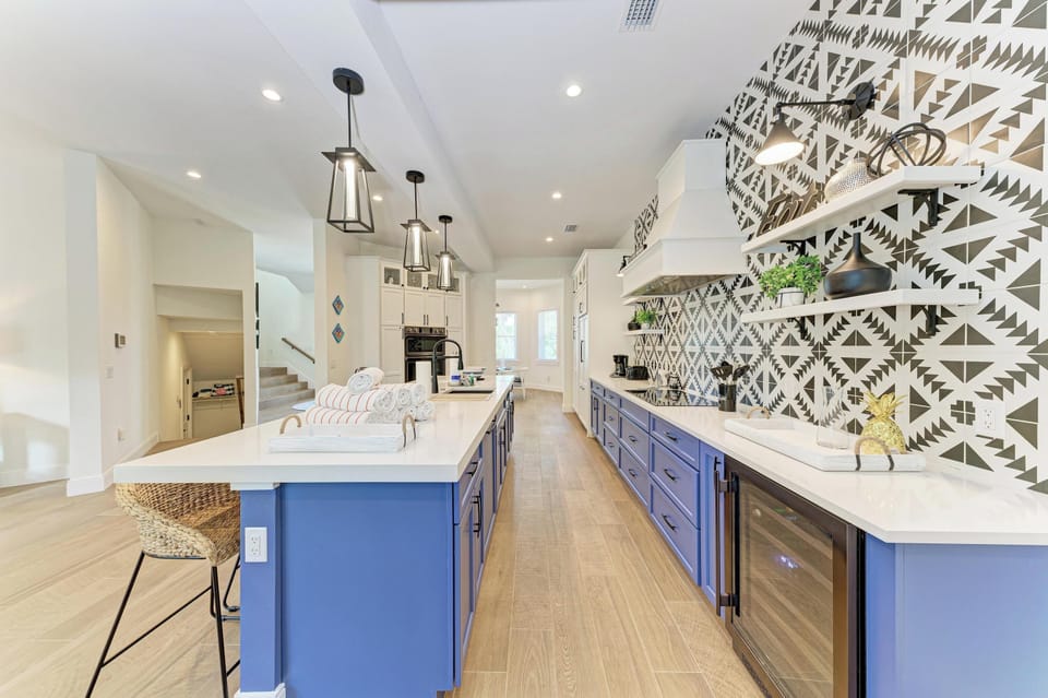 Your gourmet kitchen awaits with bold blue cabinetry, striking geometric wallpaper, and a spacious island perfect for cooking memorable meals.