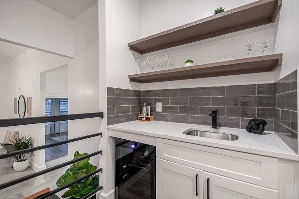 Bar area includes built in beverage fridge, bar tools, and plenty of wine and martini glasses
