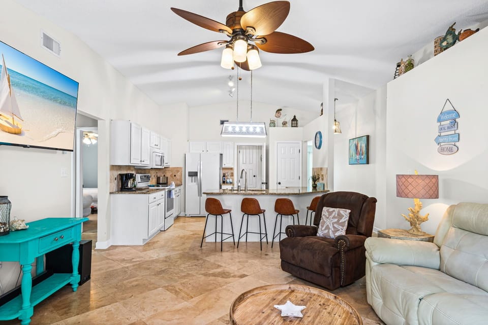 Relax in your bright, coastal-themed living space where turquoise accents and beach art create a vacation vibe.