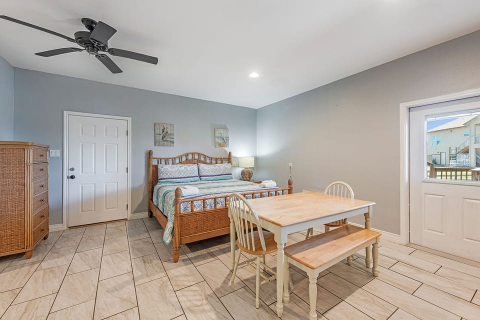 Your bright bedroom features coastal charm with wicker furniture, a comfortable queen bed, and your own dining table for morning coffee or casual meals.