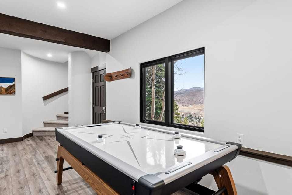 Living Room 3 / Game Room [Lower Floor]: Attached bathroom, gas fireplace, 65" Smart TV, sectional sofa, air hockey table, foosball, and dedicated workspace with desk and chair.