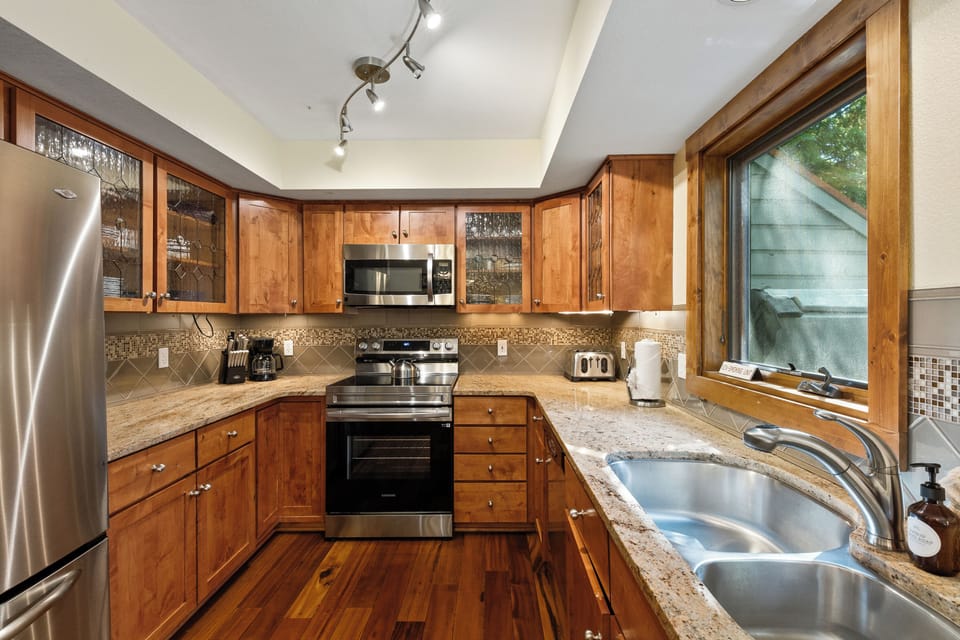 Well-stocked kitchen with view of hot tub and woods from kitchen sink window. 