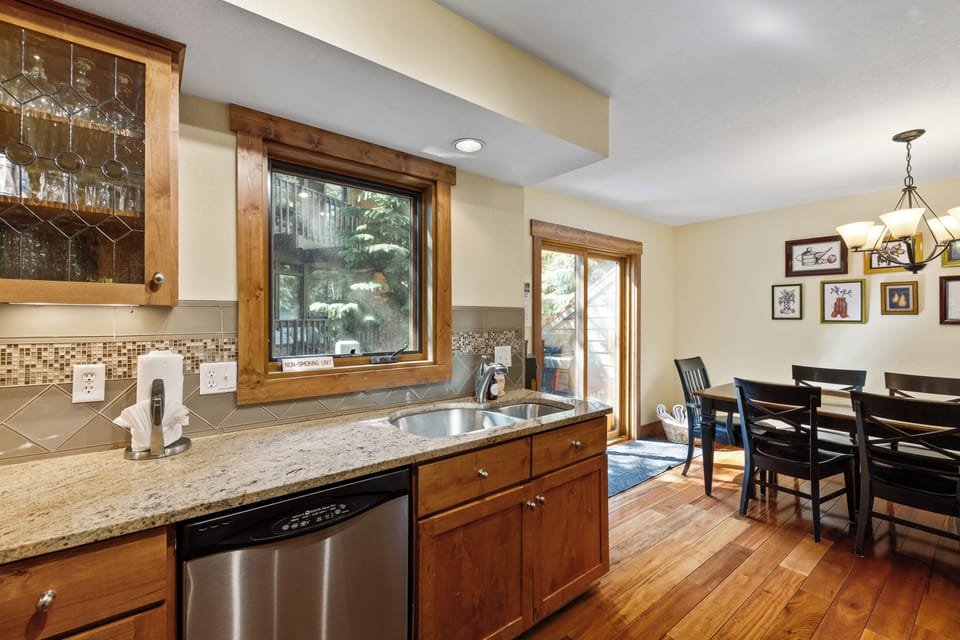 Kitchen with wood and hot tub view, balcony with hot tub and gas grill, and ample dining space. 