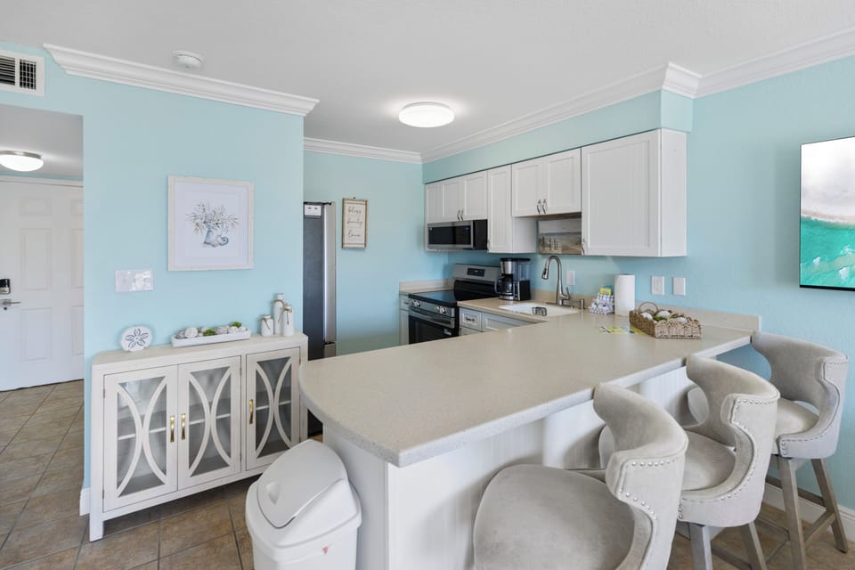 Your coastal kitchen invites you to create memorable meals with modern appliances, soothing blue walls, and a breakfast bar perfect for morning coffee.