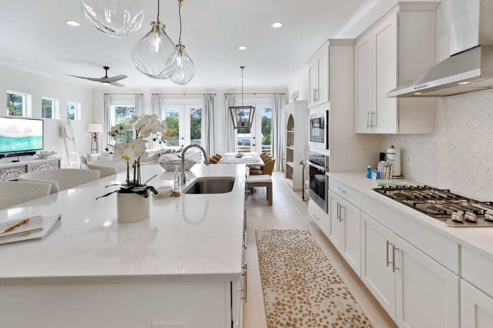 Your elegant open kitchen features pristine white cabinetry, gleaming quartz countertops, and modern appliances perfect for creating memorable meals together.
