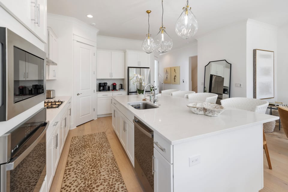 Your spacious chef's kitchen features pristine white cabinets, gleaming countertops, and elegant pendant lighting for memorable meal preparation.