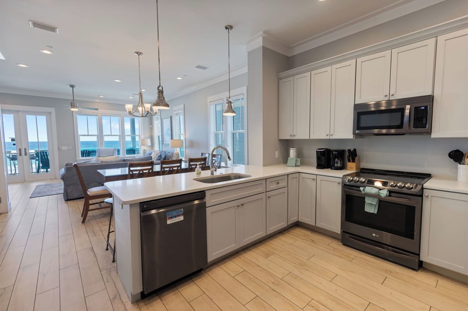 Your gourmet kitchen boasts pristine white cabinets, granite counters, and stainless steel appliances—perfect for creating memorable meals while gazing at stunning ocean views.