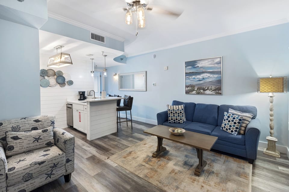 Unwind in your coastal-themed living space with plush seating and ocean artwork creating the perfect beachside retreat atmosphere.