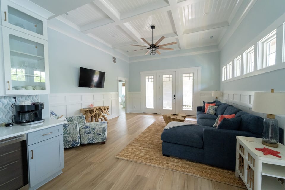 Bright coastal living room with high ceilings, sectional, and natural light