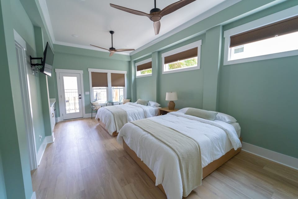 Bright double-queen bedroom with balcony access and airy coastal style