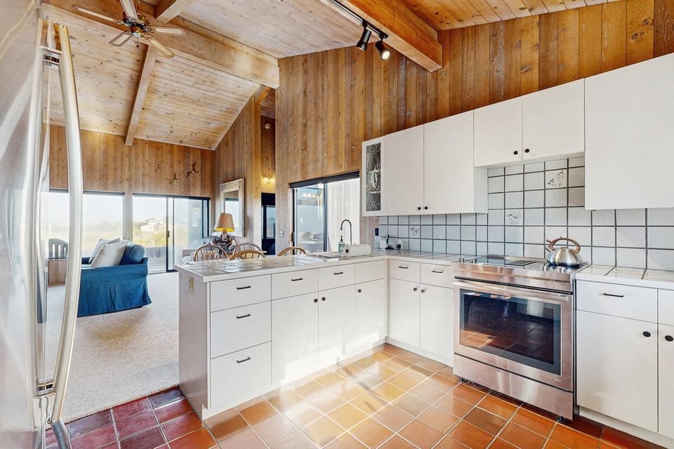 The open kitchen connects to the living and dining areas under vaulted wood ceilings -- you're never far from the conversation or the view.