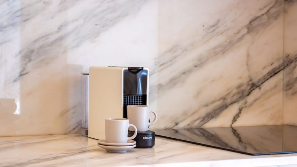 Start your day right with a fresh cup of coffee from the elegant espresso machine, served in stylish mugs on the beautiful marble countertop. #CoffeeCorner #MarbleCounter #MorningRitual #EspressoMachine #LovelyStay
