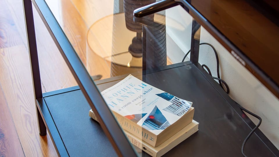 Cozy up with a good book from the curated collection, enjoying a quiet evening in or a relaxing afternoon. The warm wooden floors and inviting decor create a perfect sanctuary for unwinding.