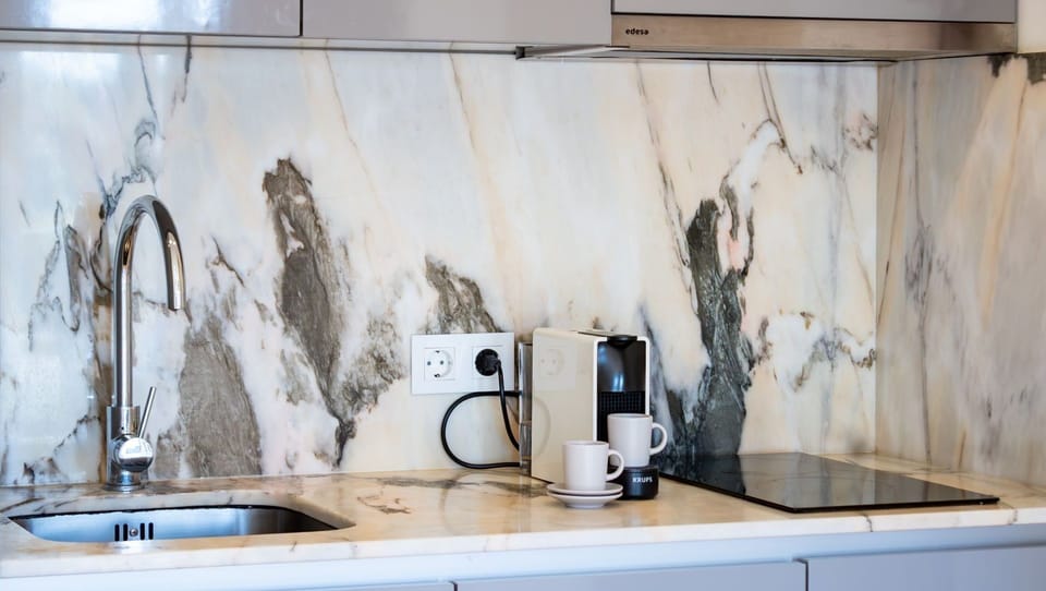 Prepare a delightful meal or your favorite espresso in this sleek and modern kitchenette, featuring elegant marble finishes and all the essentials for a comfortable stay. Enjoy the convenience of a well-appointed space right within your apartment.