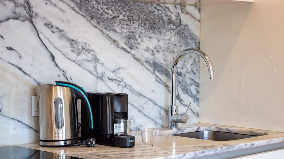 Prepare your favorite hot beverages with ease in this stylish kitchenette, complete with a gleaming sink and elegant marble-effect backsplash. It's perfectly equipped for your morning coffee or evening tea rituals.