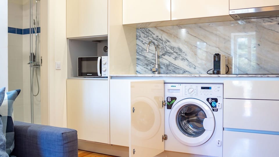 This clever kitchen design maximizes space and convenience, featuring a sleek marble backdrop, integrated appliances, and even a tucked-away washing machine for all your laundry needs. Enjoy the ease of home-cooked meals and fresh clothes during your stay