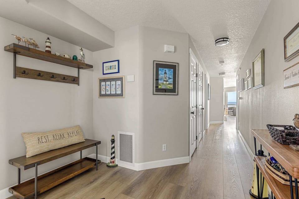 Well-designed hallway with wood floors, coastal accents, and convenient layout connecting all living spaces.