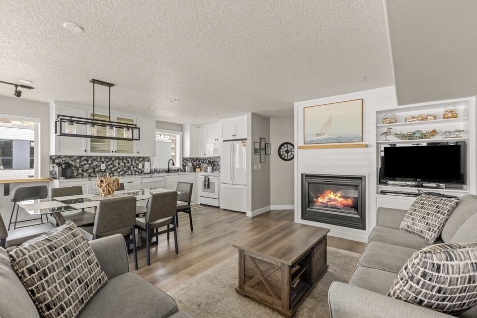 Enjoy open-concept living with modern kitchen, dining table, and cozy fireplace in this beachfront retreat.