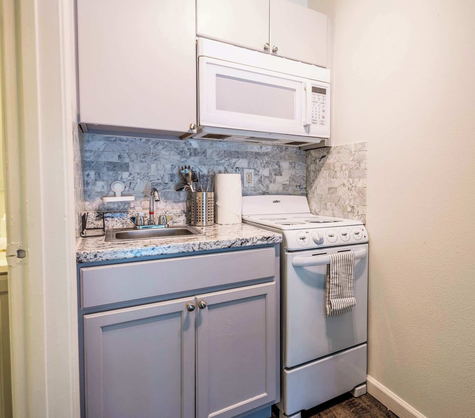 Modern studio kitchen with sleek appliances and chic marble backsplash, ideal for cozy meal prep.