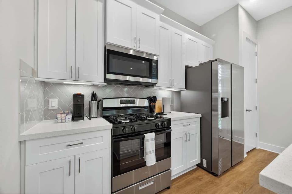 The fully equipped gourmet kitchen features premium stainless steel appliances, including a double-door refrigerator and gas range.
