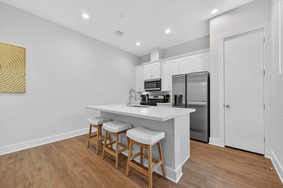Fully equipped with stainless steel appliances, white shaker cabinetry, and breakfast bar seating.