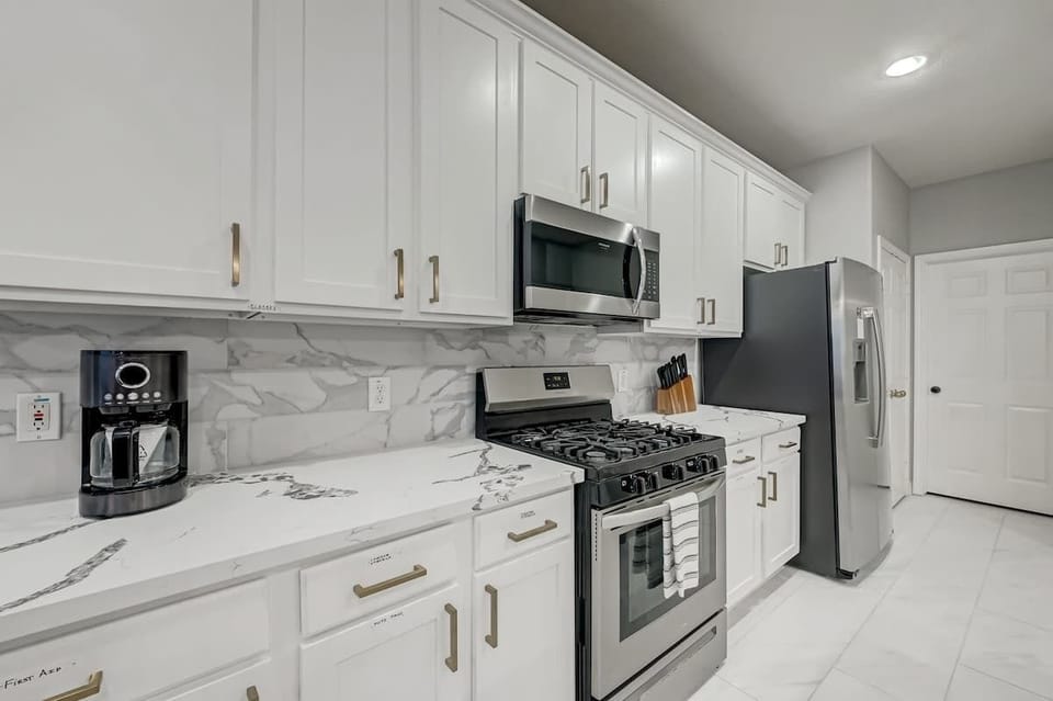 Bright cooking space with stainless steel stove, microwave, and generous storage.

