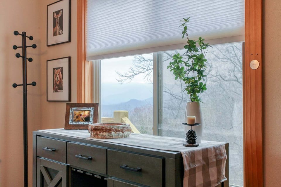 Interior seating area positioned beside a large picture window overlooking mountain scenery. Natural light and Smoky Mountain views enhance the cabin atmosphere.