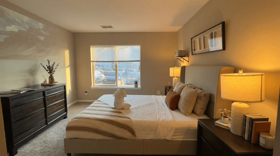 King bedroom with dresser, lamps and window