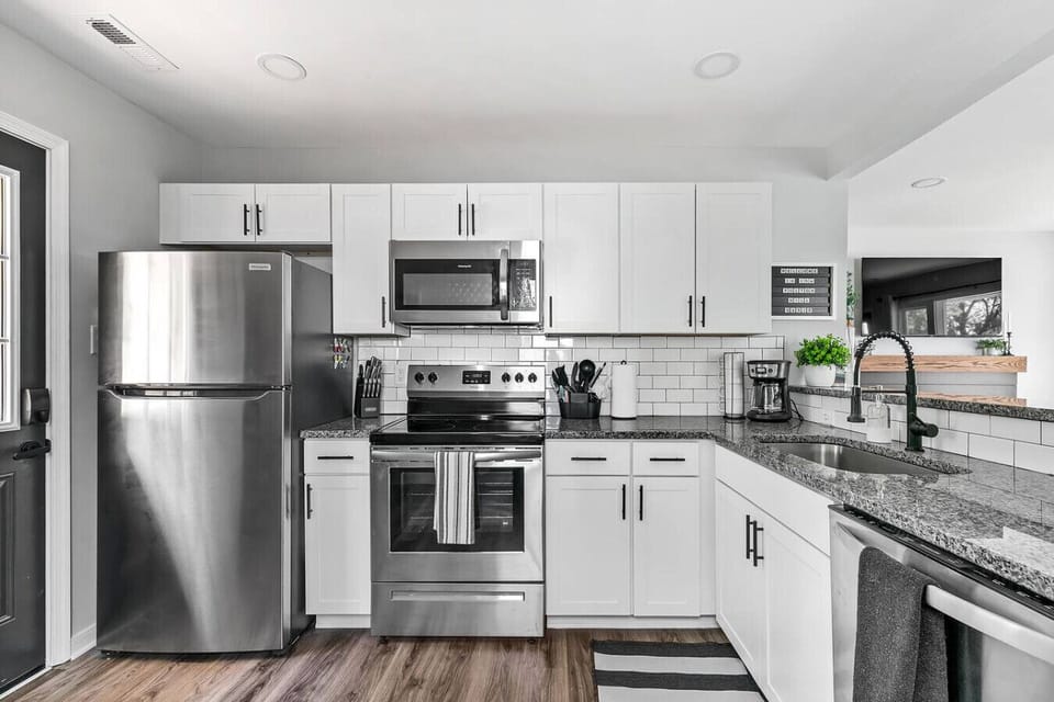 A fully stocked, modern kitchen with fresh appliances, dishwasher, microwave, drip coffee, and oven/stove—perfect for cooking, gathering, and fueling up before heading downtown or to the airport just minutes away.