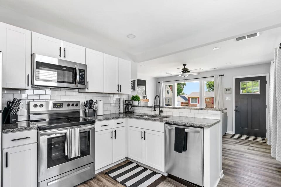 A fully stocked, modern kitchen with fresh appliances, dishwasher, microwave, drip coffee, and oven/stove—perfect for cooking, gathering, and fueling up before heading downtown or to the airport just minutes away.