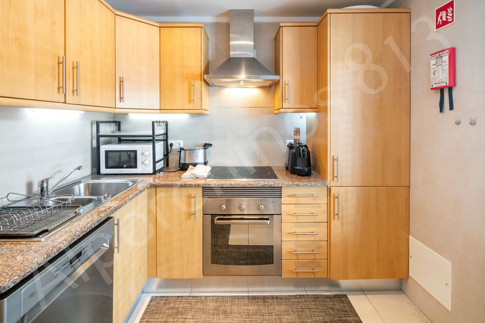 Fully equipped kitchen at 813 Alporchinhos featuring warm wooden cabinetry, granite worktops, a built-in oven and ceramic hob with stainless steel extractor hood, coffee machine, and ample storage, providing everything needed for self-catering during your Algarve holiday