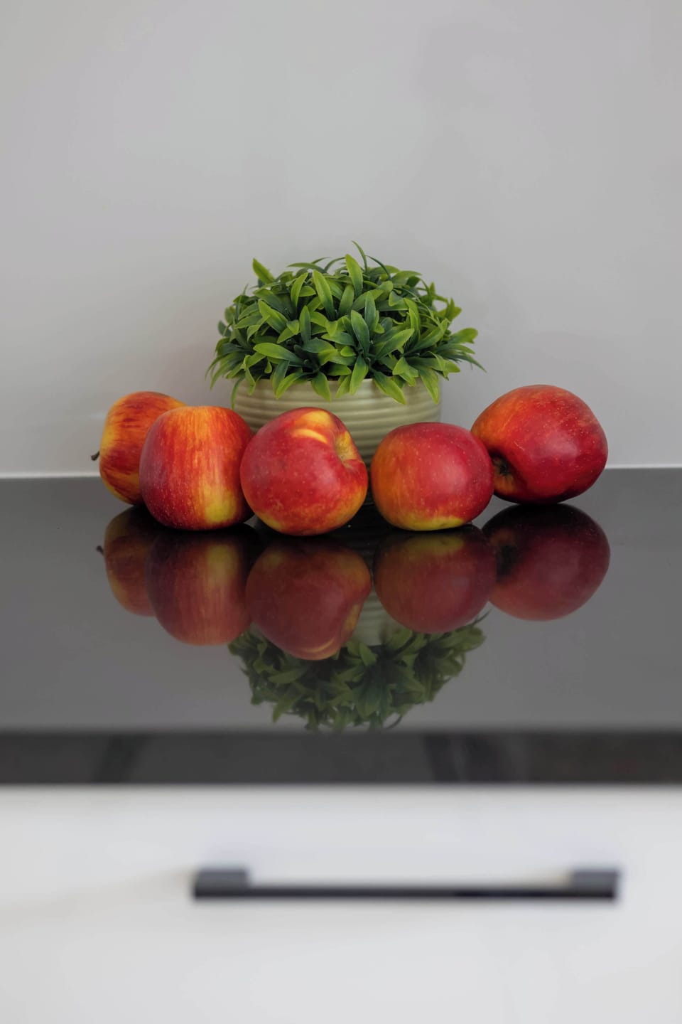 A close-up view of the kitchen counter showcasing a cluster of red apples and a small green potted plant.