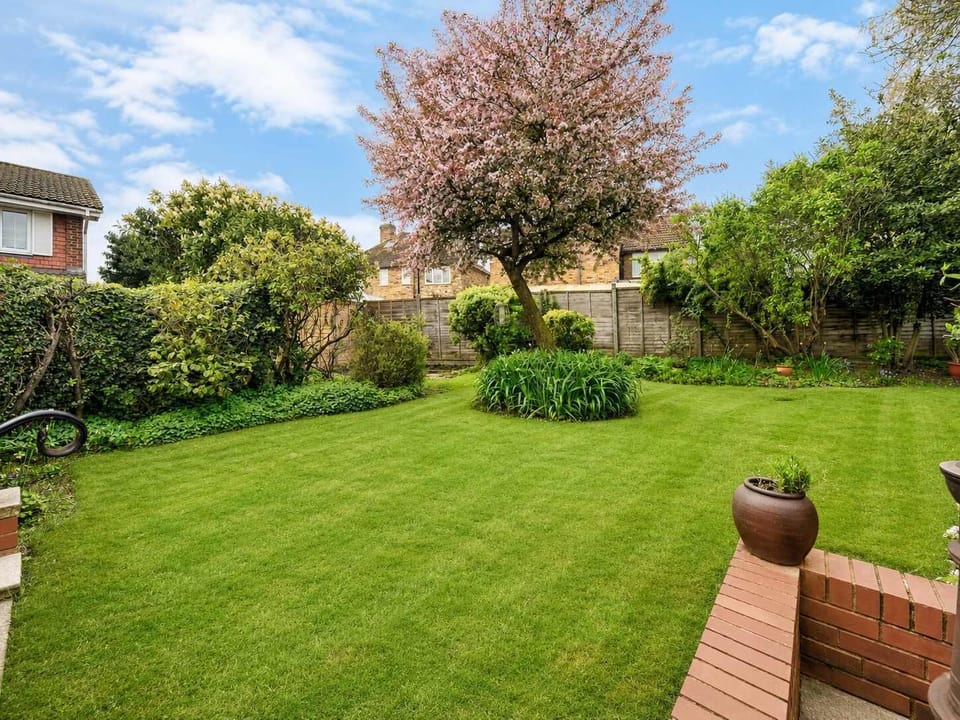 Garden: Spacious lawn framed by lush green hedges and a stunning blossoming tree creates a peaceful outdoor escape!