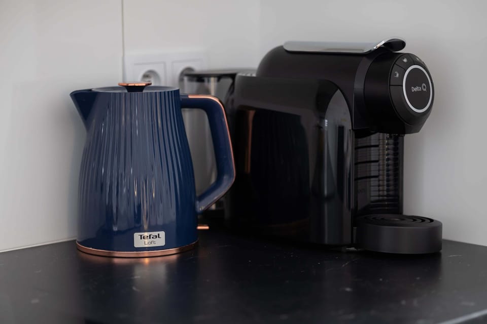 A close-up of kitchen appliances including an electric kettle and a coffee machine placed on the countertop. The setup highlights convenience for preparing hot drinks.