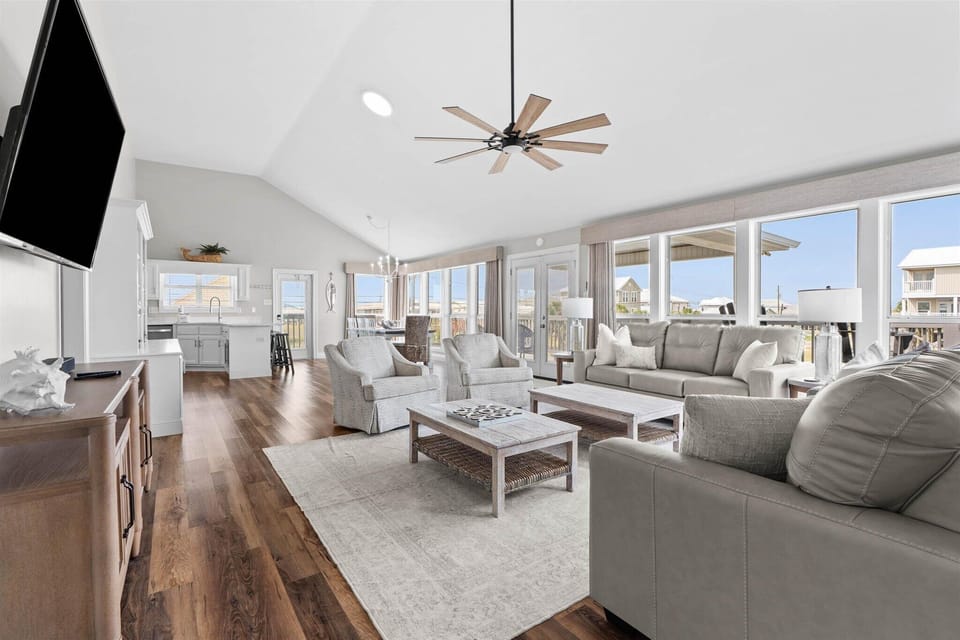Relax in your spacious living room with plush seating, stunning views, and coastal breezes from the ceiling fan overhead.