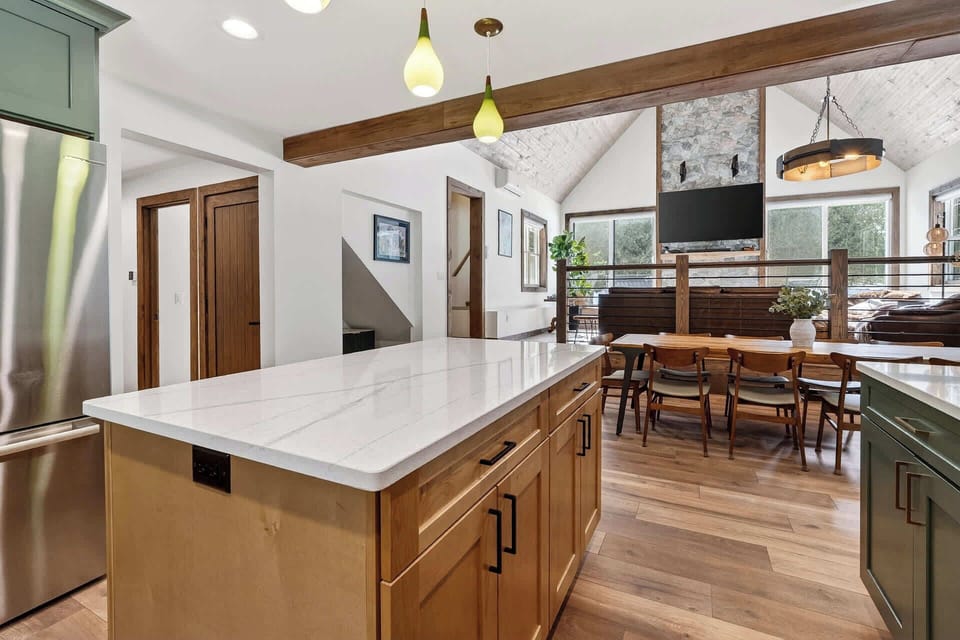 Gather with loved ones in this stunning open kitchen featuring marble countertops, exposed beams, and a welcoming dining area.