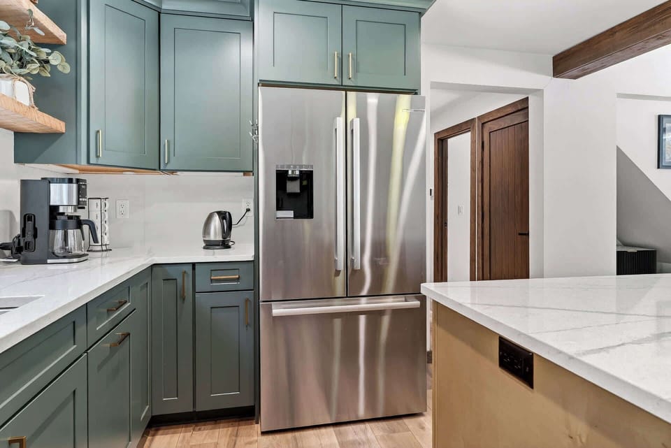 You'll love cooking in this stylish kitchen with sage green cabinets, gleaming stainless appliances, and spacious marble countertops perfect for meal prep.
