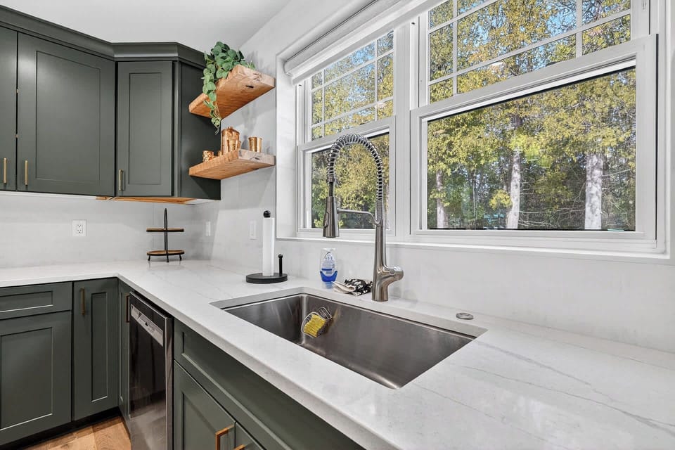 You'll love cooking in this bright kitchen with sage-green cabinets, marble counters, and garden views streaming through large windows.