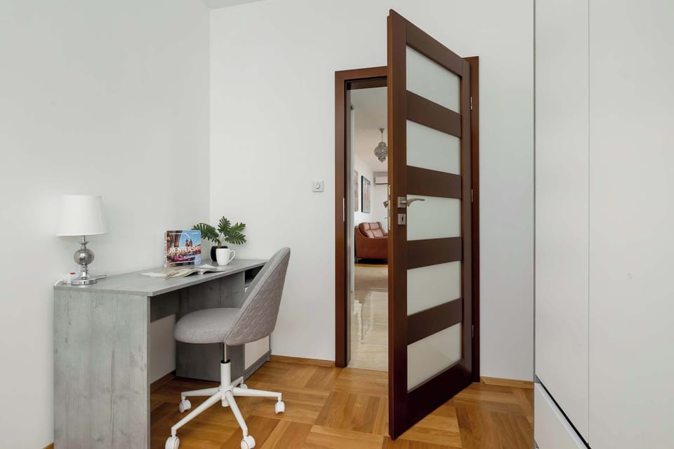 A sleek white desk and an ergonomic grey chair provide a dedicated space for remote work or study. The room is uncluttered, promoting a peaceful and productive environment.