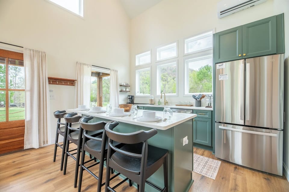 Your stunning kitchen features sage green cabinetry, stainless steel appliances, and a spacious island perfect for morning coffee or evening meals together.