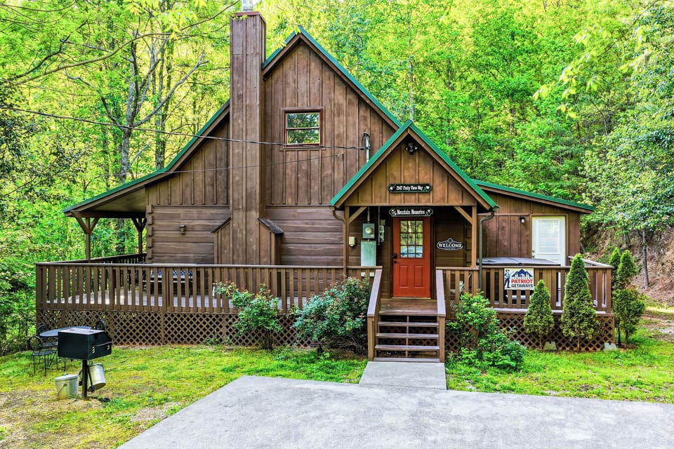 Charming wooden cabin nestled in lush forest surroundings with welcoming front entrance and outdoor grilling space.