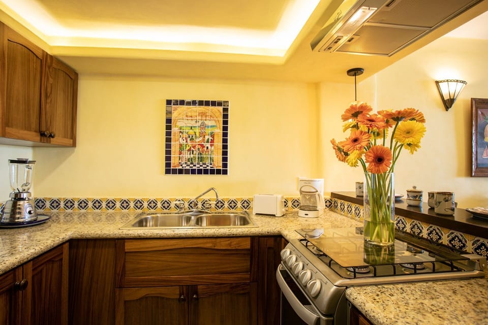 The cozy kitchen is adorned with traditional Mexican tiles and vibrant flowers, creating an inviting atmosphere for culinary adventures.