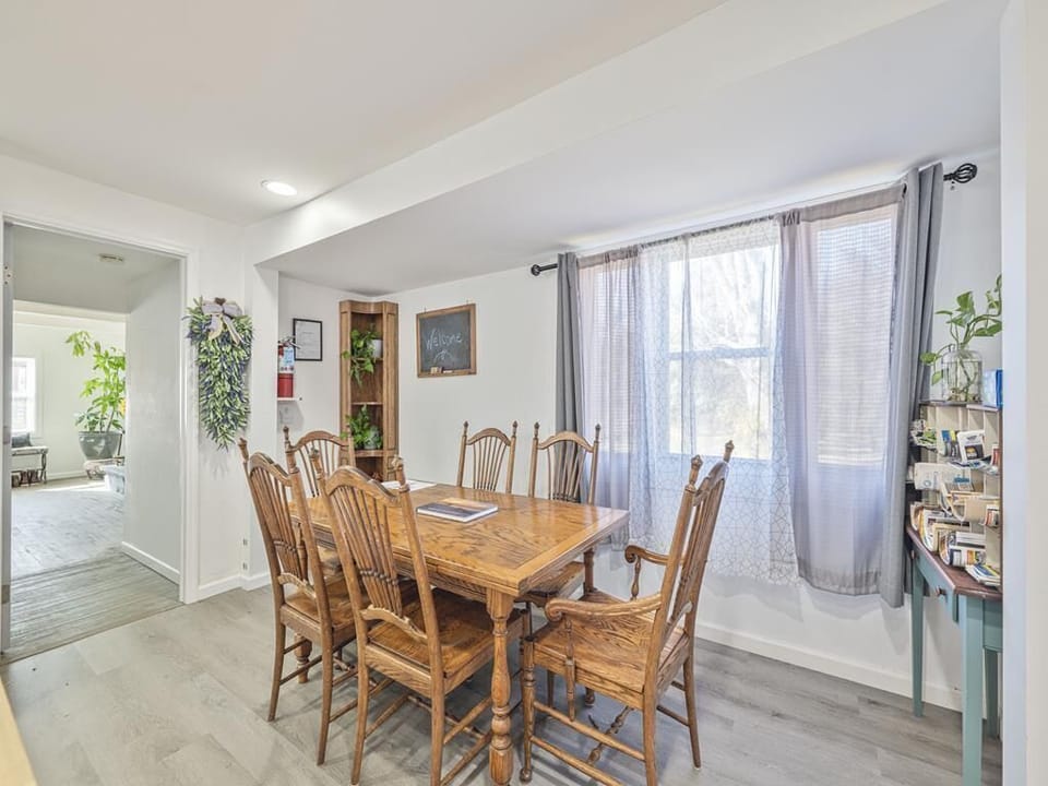 Gather around the wooden dining table — there's room for the whole group, with plenty of natural light to set the mood.