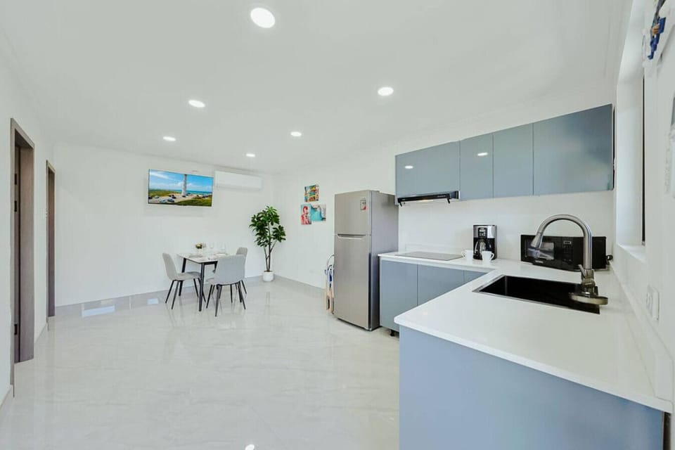 Apartment B offers a stylish, fully equipped kitchen with contemporary finishes, generous counter space, and a dining area for three—ideal for relaxed and easy home meals.