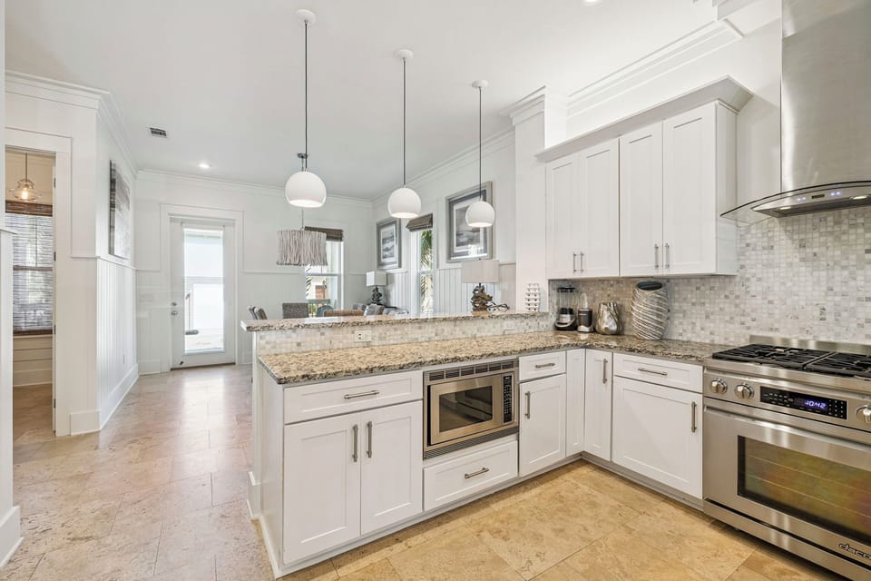 Cook with ease in this bright, modern kitchen featuring granite counters, stainless appliances, and elegant pendant lighting.
