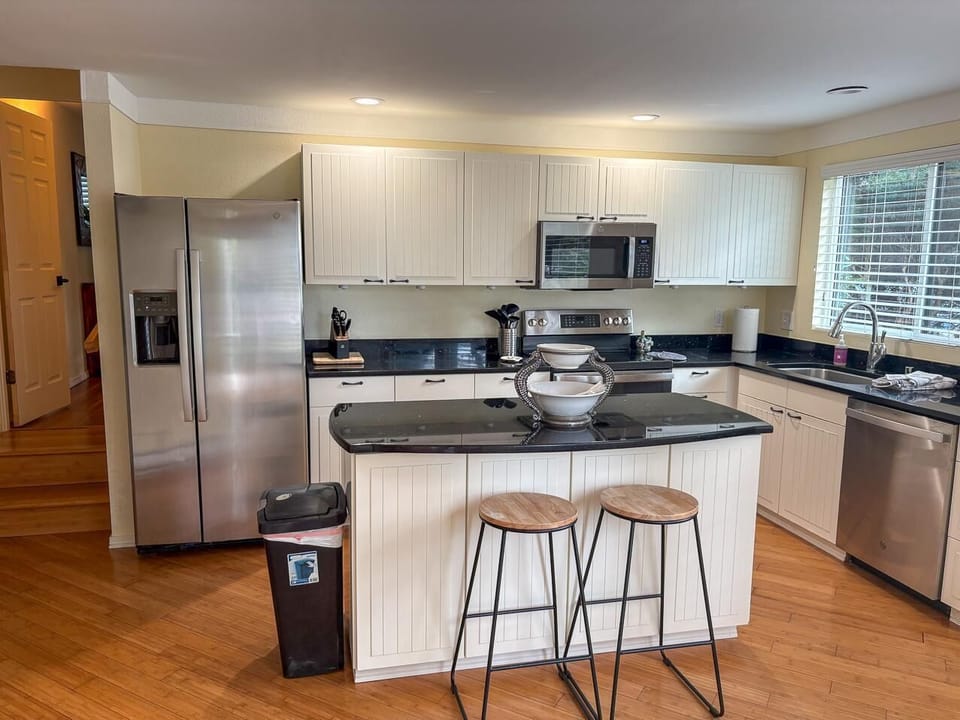 Black granite counters contrast with white cabinetry and stainless steel appliances in the kitchen.