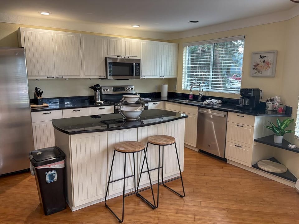 Black granite countertops contrast with white paneled cabinets and stainless steel appliances in the kitchen.